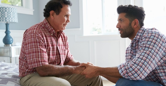 Adult son comforting his elderly father